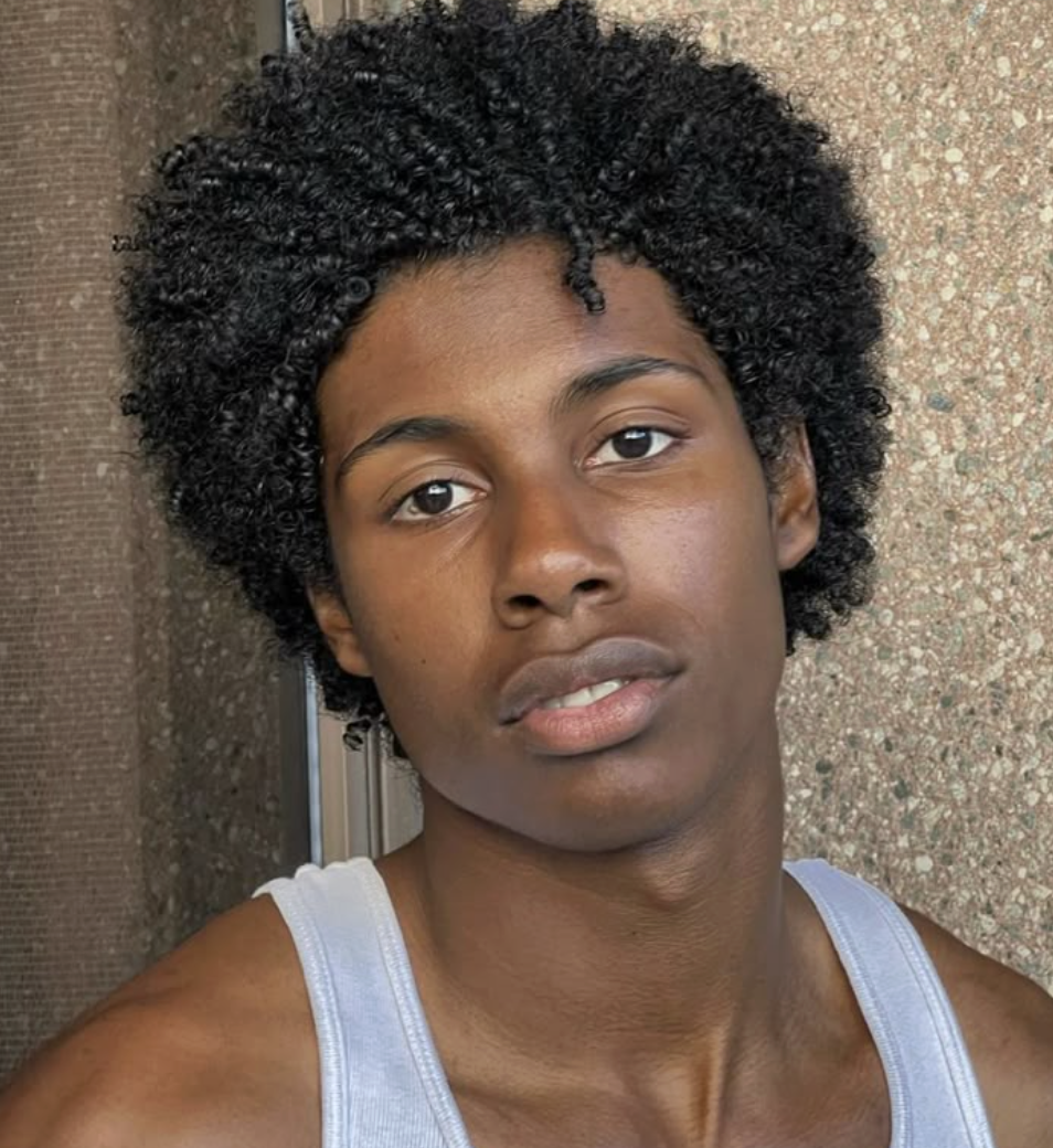 homme de couleur avec afro bouclé avec la bouche très légèrement ouvert et un regard intense