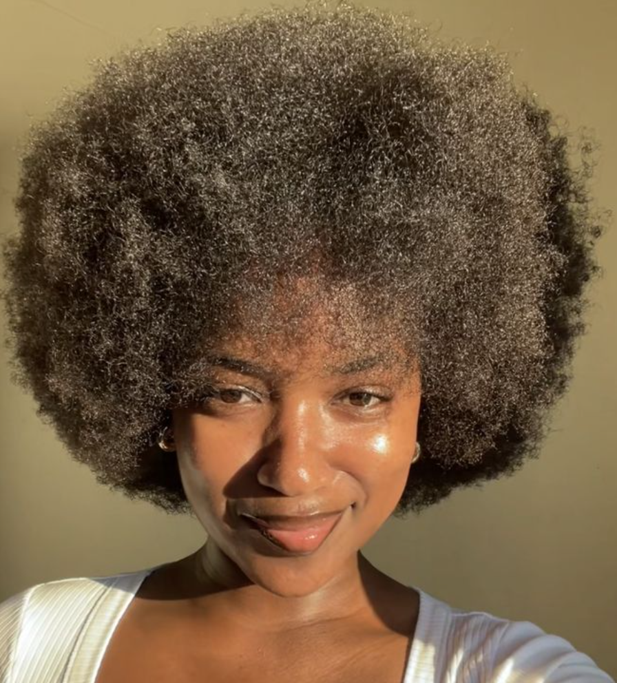 Femme de couleur avec cheveux afro faisant un sourire